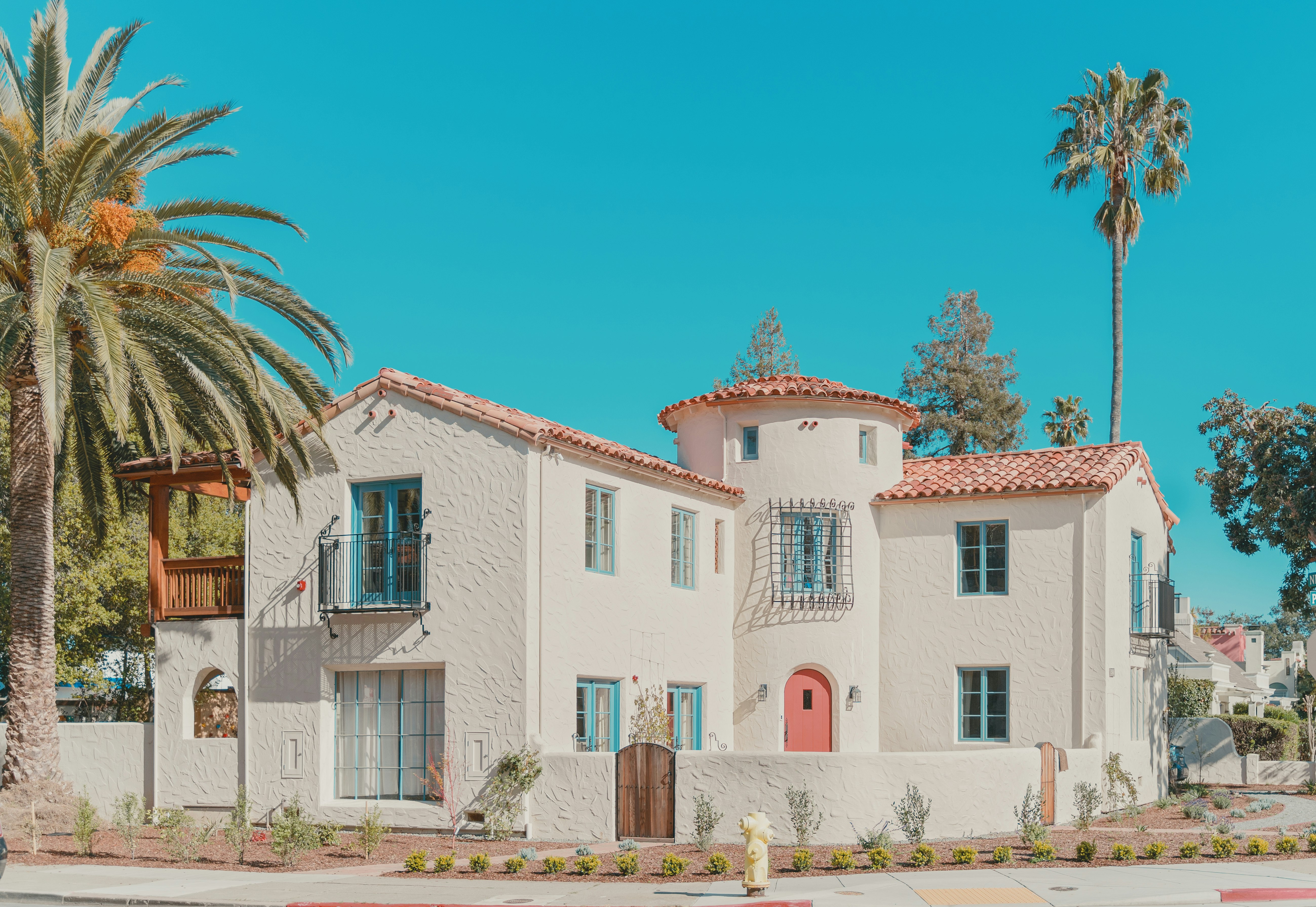 white and pink concrete building near palm trees under blue sky during daytime